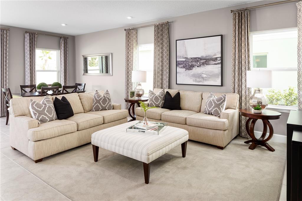 A living room features two beige sofas, a striped ottoman, and two side tables with lamps — 2614 LANDING DRIVE, TITUSVILLE, FL