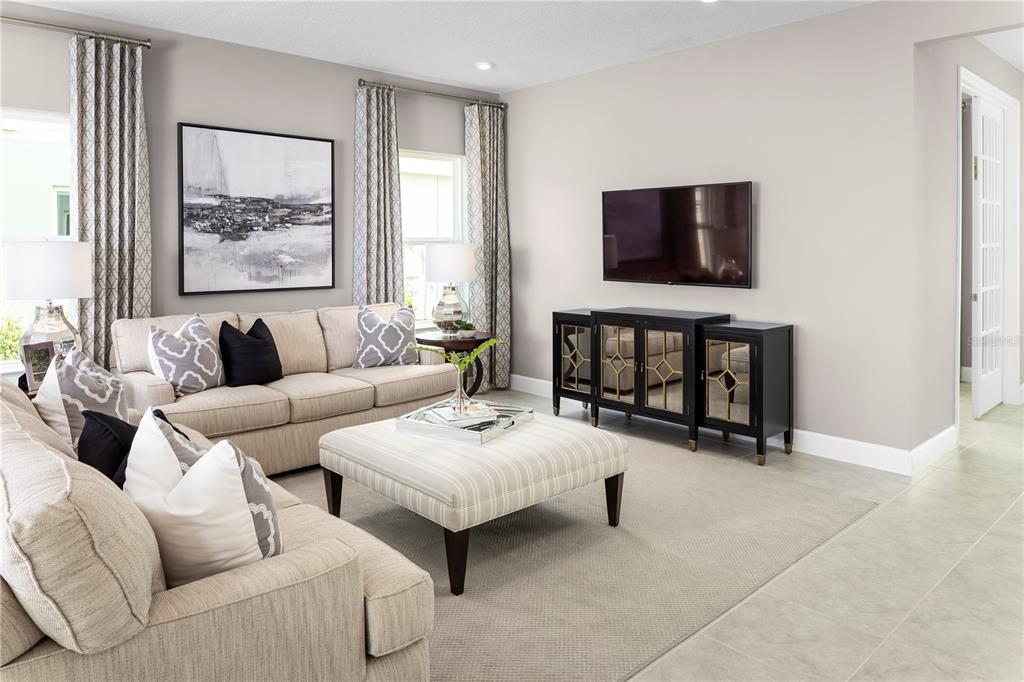 A living room features a beige sofa, a striped ottoman, and a black media console — 2614 LANDING DRIVE, TITUSVILLE, FL