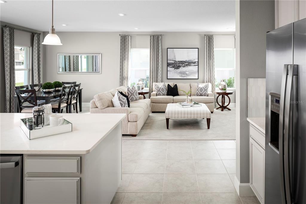 An open-concept living and dining area features neutral furniture, tile flooring, and large windows — 2614 LANDING DRIVE, TITUSVILLE, FL