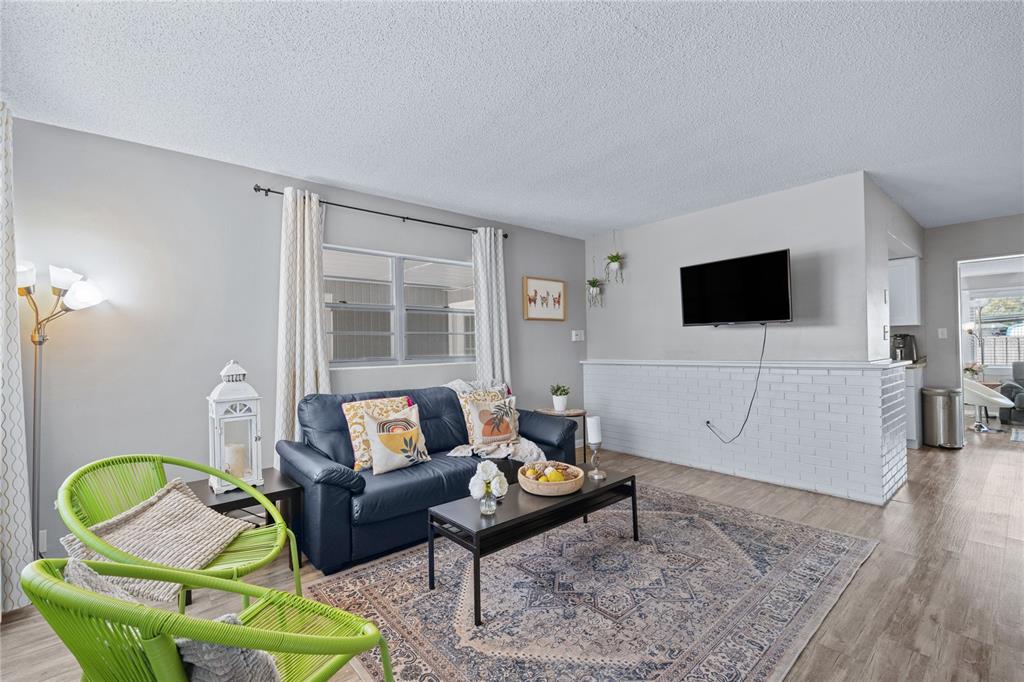 A living room features a dark sofa, two green chairs, and a white brick wall — 5320 BRERETON AVENUE, ORLANDO, FL