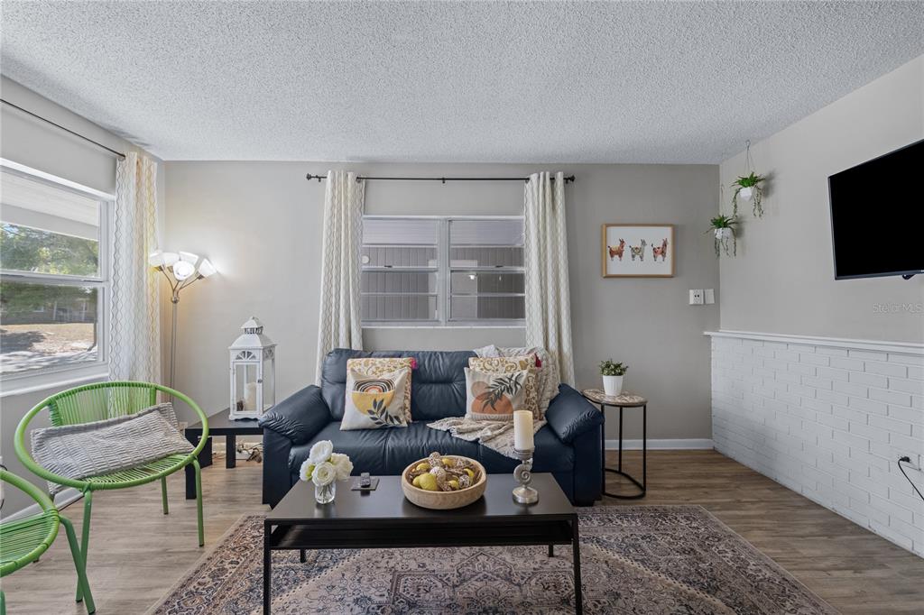 A living room features a dark blue sofa, a coffee table, and green accent chairs — 5320 BRERETON AVENUE, ORLANDO, FL