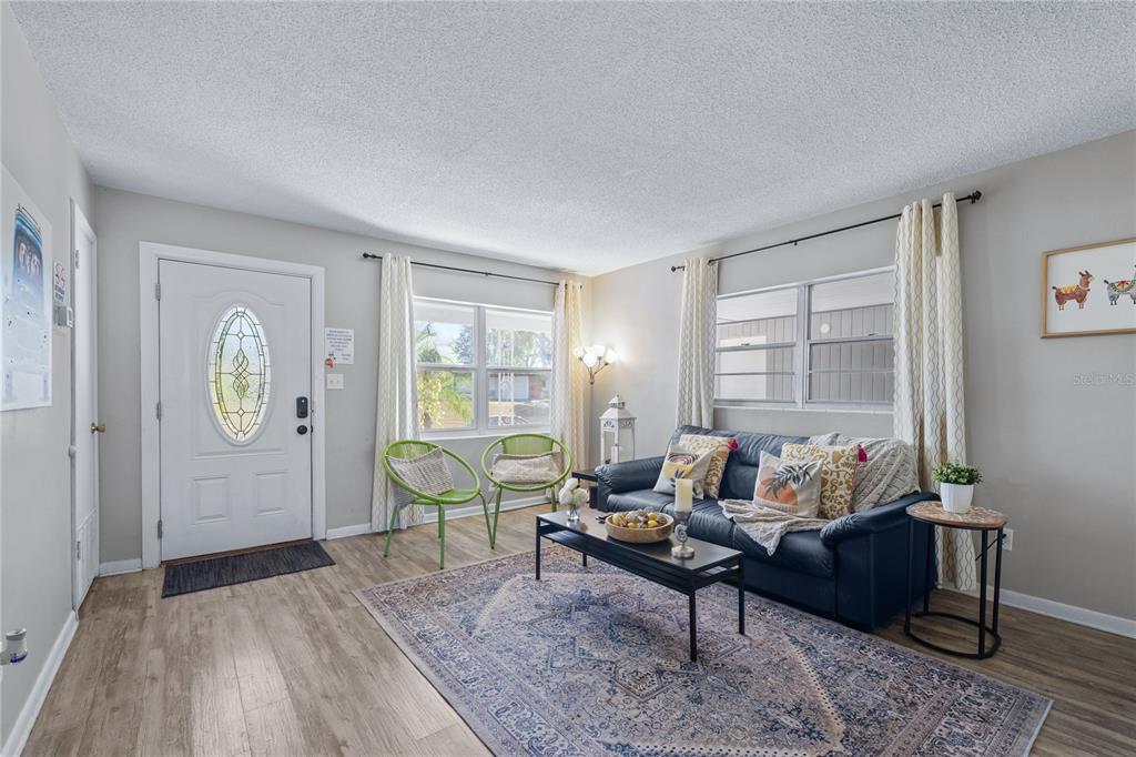 A living room features a dark sofa, a patterned area rug, and two green chairs — 5320 BRERETON AVENUE, ORLANDO, FL