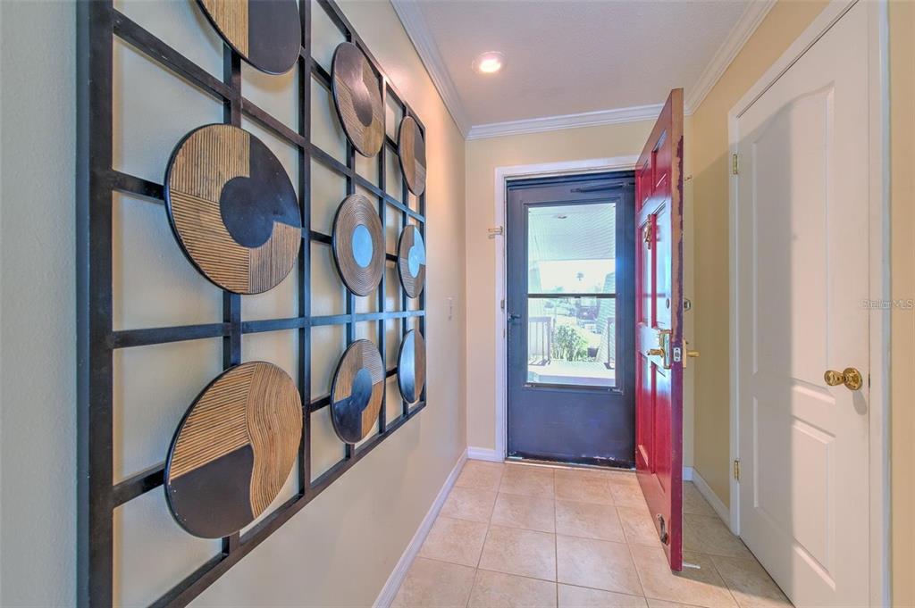 An entryway features a red front door, tiled flooring, and a large decorative metal wall art — 1008 APOLLO BEACH BOULEVARD UNIT 201, APOLLO BEACH, FL