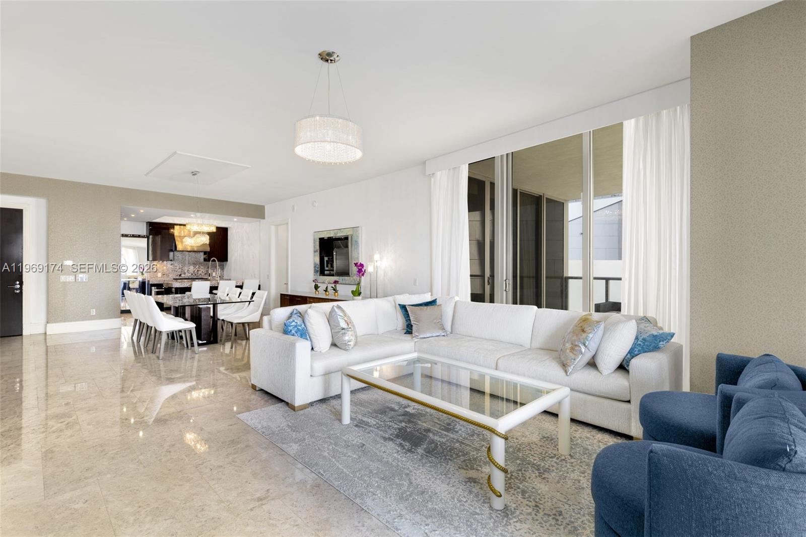 A living room with a white sectional sofa, glass coffee table, and adjacent dining area — 9701 Collins Ave # 404S, Bal Harbour FL 33154, BAL HARBOUR, FL