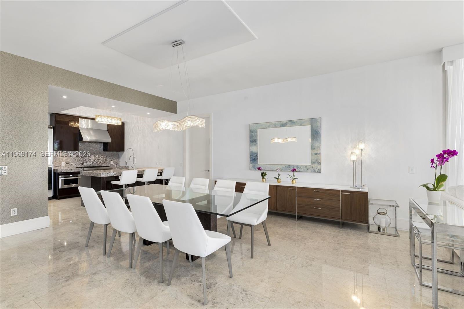 A dining room features a glass table, white chairs, a wooden sideboard, and marble flooring — 9701 Collins Ave # 404S, Bal Harbour FL 33154, BAL HARBOUR, FL