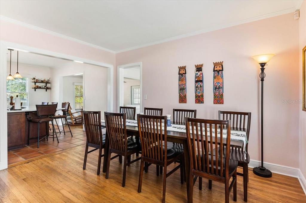A dining room with a wooden table, chairs, and wall art, adjacent to a kitchen — 2514 15TH AVENUE W, BRADENTON, FL