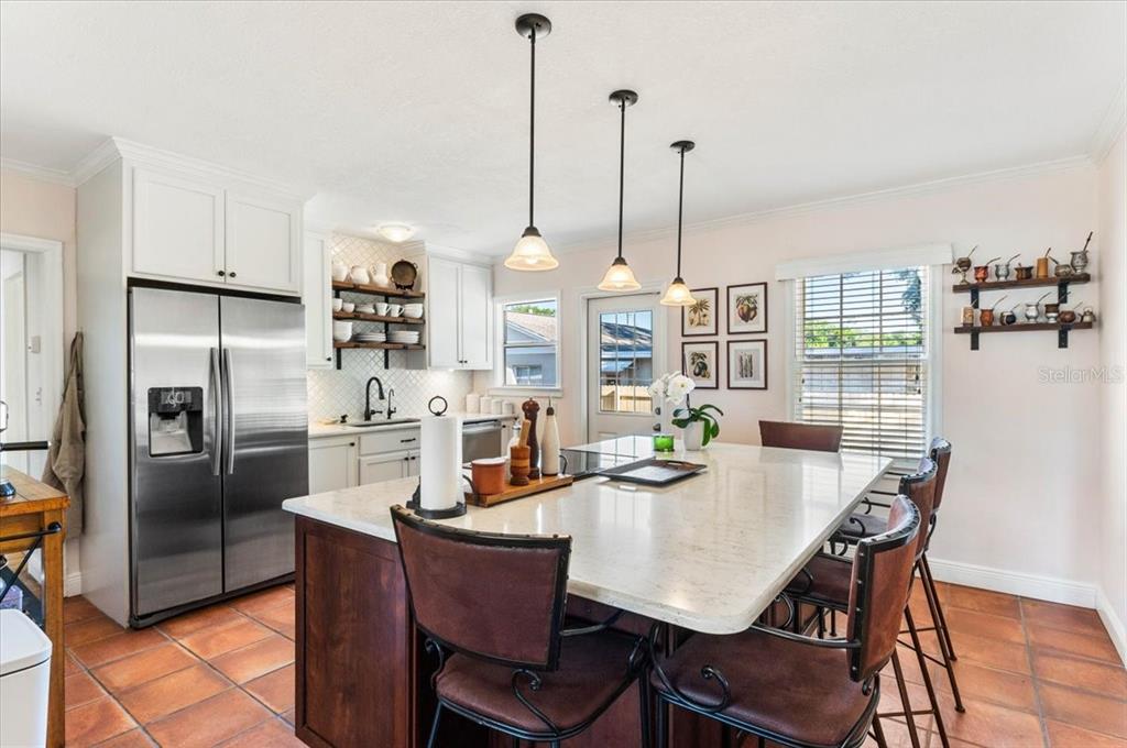 A kitchen features a large island with bar seating, white cabinetry, and tile flooring — 2514 15TH AVENUE W, BRADENTON, FL