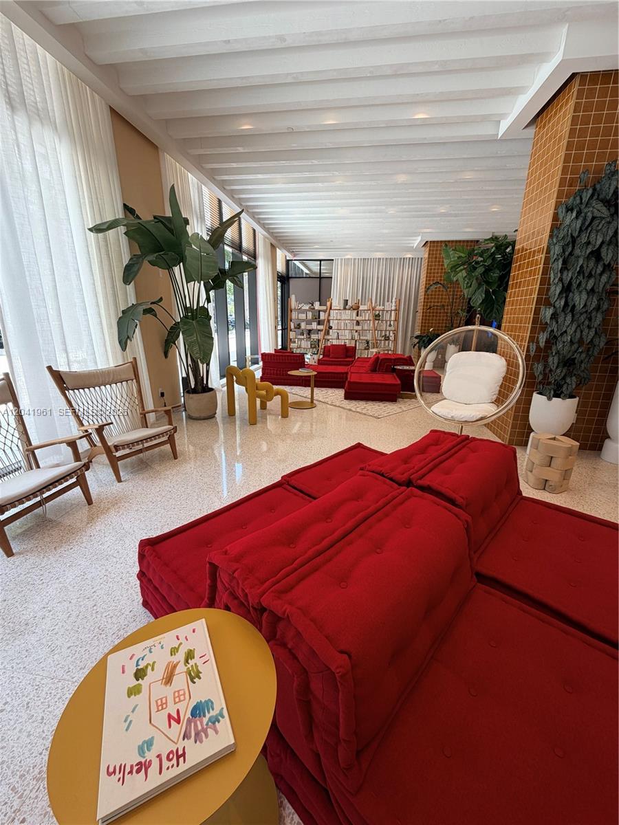 A modern lounge area features red modular seating, a hanging chair, and large potted plants — 90 NE 32nd St # 702, Miami FL 33137, MIAMI, FL
