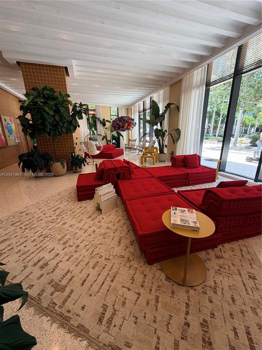 A modern lobby features red modular seating, large potted plants, and floor-to-ceiling windows — 90 NE 32nd St # 702, Miami FL 33137, MIAMI, FL