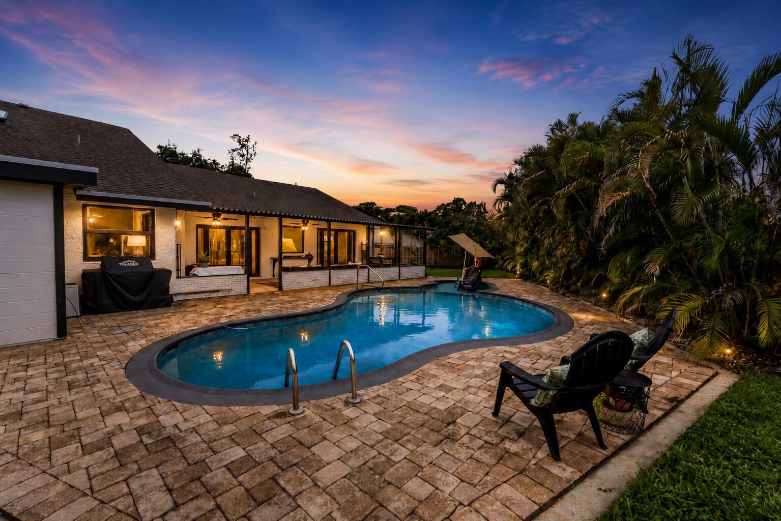 A backyard patio with a kidney-shaped pool, brick pavers, and a house at sunset — 5731 NW 54th Way, Tamarac FL 33319, TAMARAC, FL
