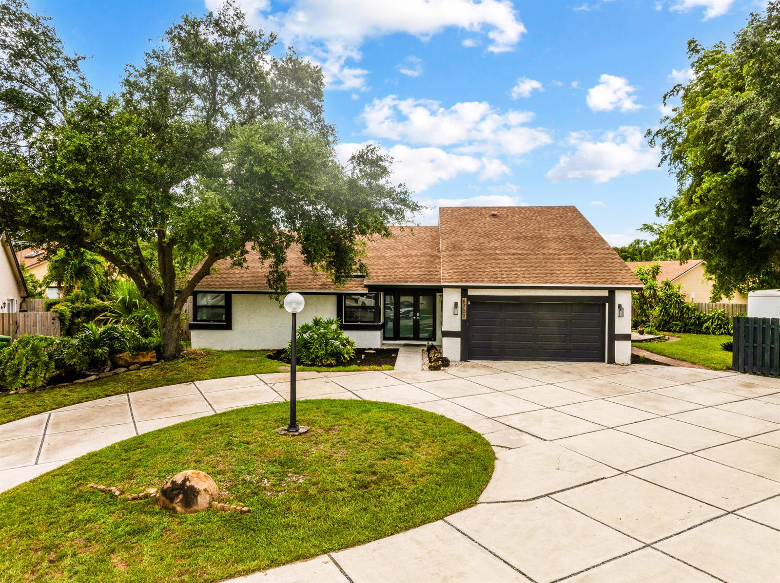 A single-story house with a white exterior, dark garage door, and a large circular driveway — 5731 NW 54th Way, Tamarac FL 33319, TAMARAC, FL
