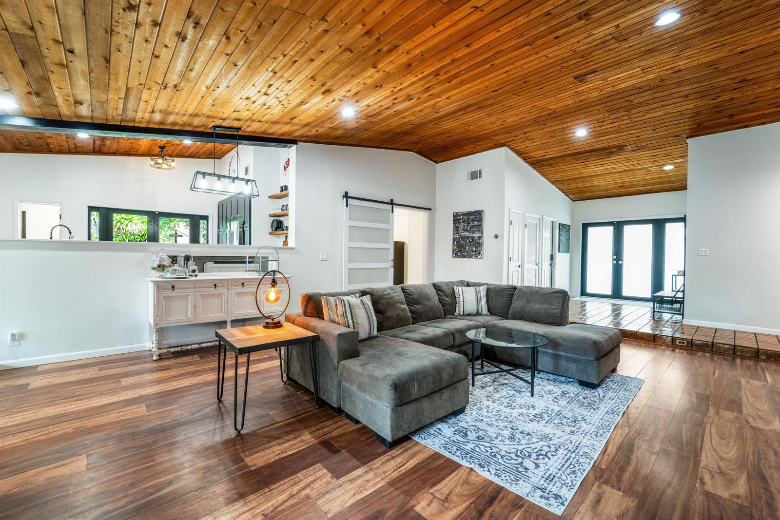 A living room features a vaulted wood-plank ceiling, a gray sectional sofa, and wood flooring — 5731 NW 54th Way, Tamarac FL 33319, TAMARAC, FL