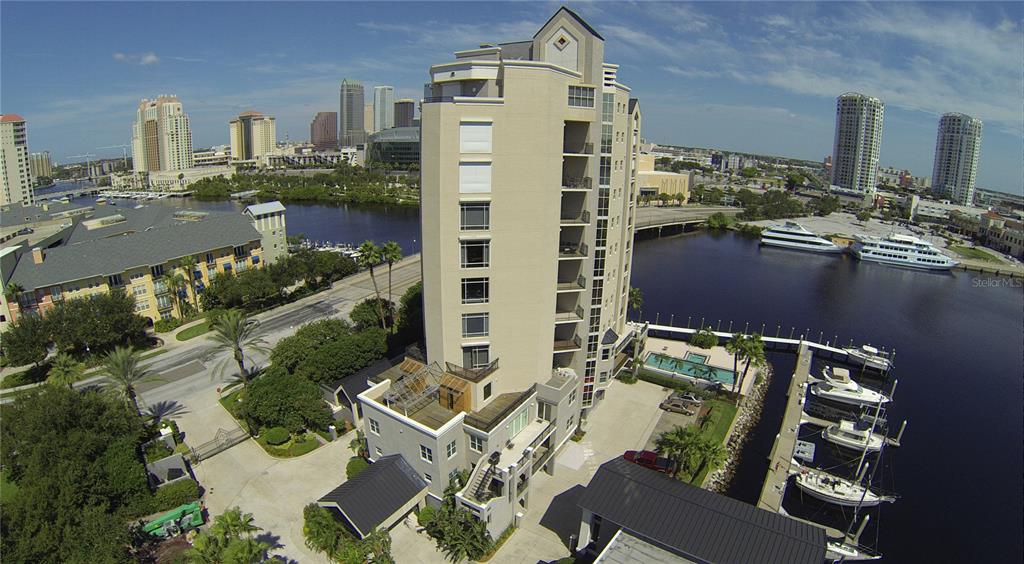 An aerial view shows a tall residential building next to a river with docked boats — 600 GARRISON COVE LANE UNIT 1, TAMPA, FL