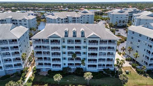 An aerial view shows several multi-story residential buildings with balconies surrounded by palm trees — 700 CINNAMON BEACH WAY UNIT 633, PALM COAST, FL