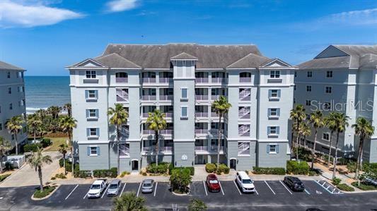 An aerial view shows a multi-story light-colored apartment building with a parking lot in front — 700 CINNAMON BEACH WAY UNIT 633, PALM COAST, FL