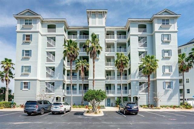 A multi-story light blue apartment building with palm trees and parked cars in front — 700 CINNAMON BEACH WAY UNIT 633, PALM COAST, FL