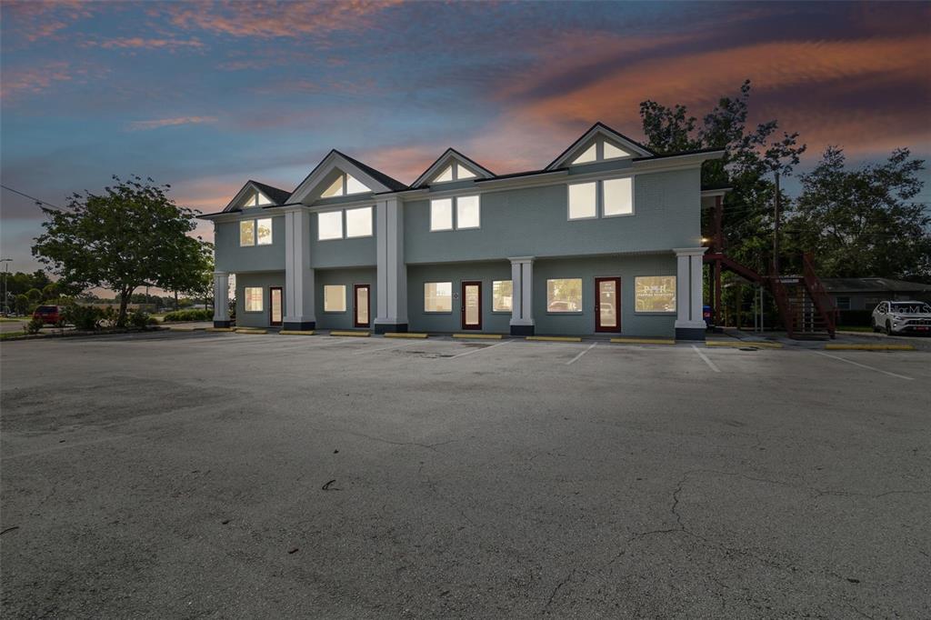 A two-story commercial building with a large parking lot under a sunset sky — 1137 BARTOW ROAD UNIT 204, LAKELAND, FL