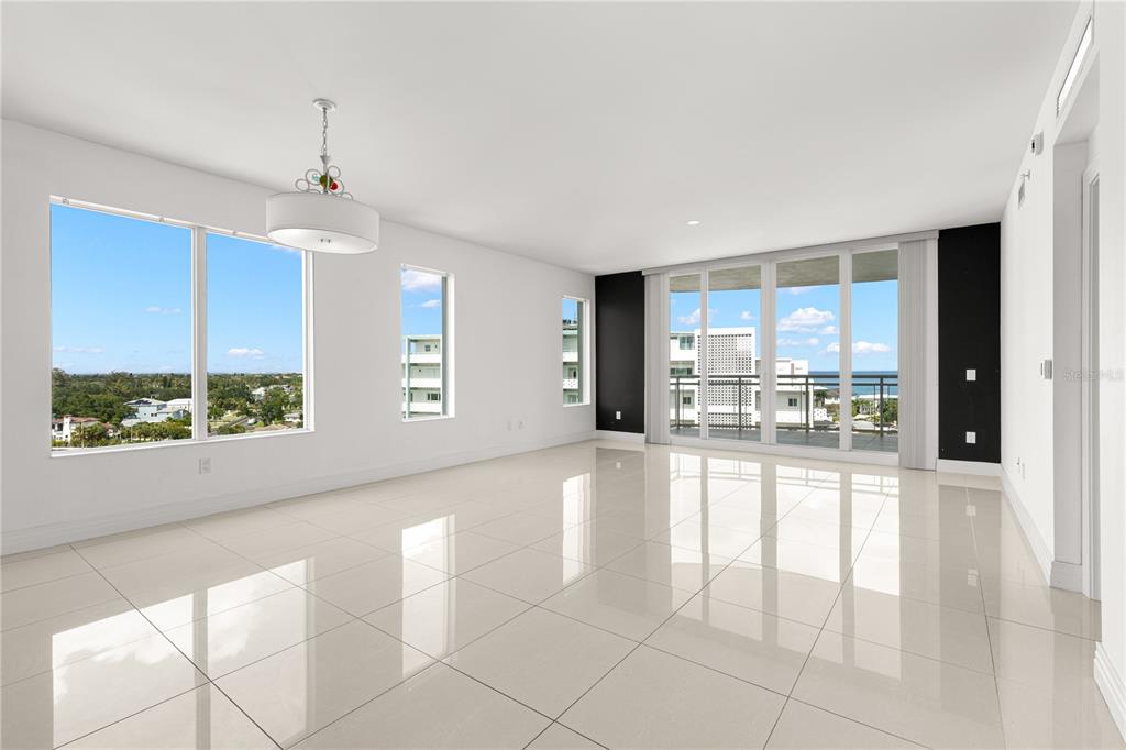 A bright, modern living room features white tile floors, large windows, and a balcony view — 1325 SNELL ISLE BOULEVARD NE UNIT 812, ST PETERSBURG, FL