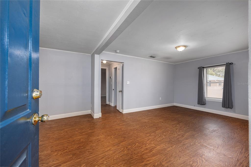 A room with light gray walls, wood-look flooring, and a doorway leading to a hallway — 1001 NE 2ND AVENUE, TRENTON, FL