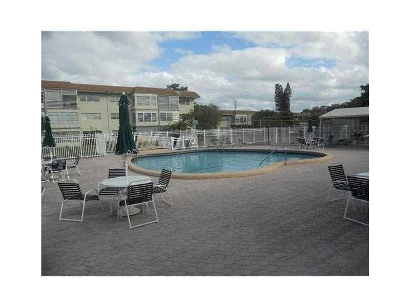 A swimming pool is surrounded by a paved patio with outdoor tables and chairs — 613 S State Road 7 # 3E, Margate FL 33068, MARGATE, FL