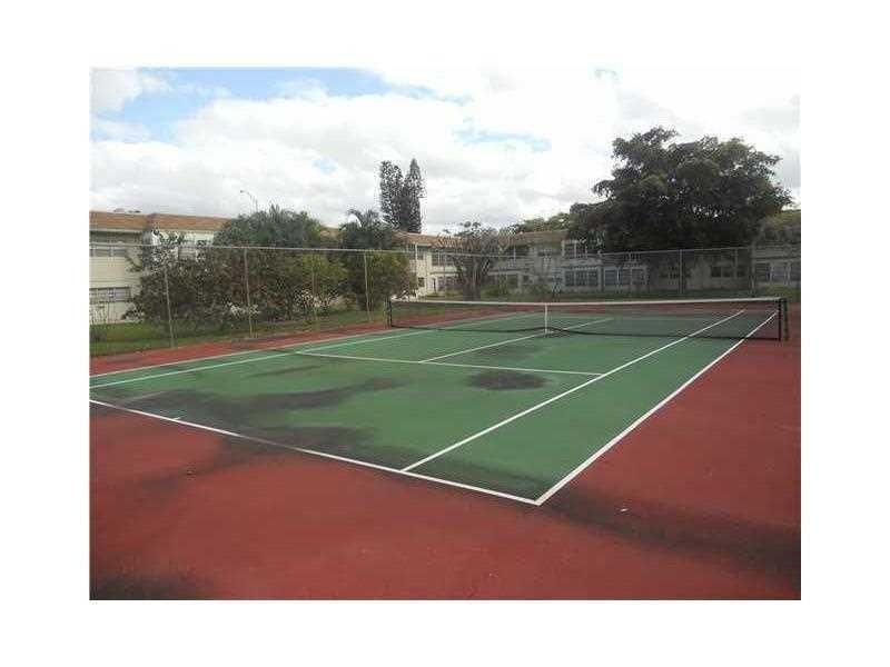 A weathered outdoor tennis court with a net is surrounded by a chain-link fence — 613 S State Road 7 # 3E, Margate FL 33068, MARGATE, FL