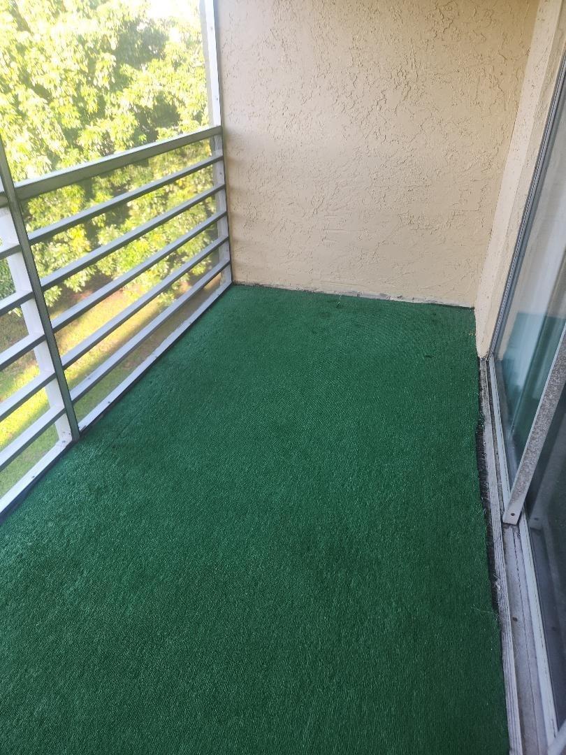 A balcony with green outdoor carpeting, a metal railing, and a sliding glass door — 613 S State Road 7 # 3E, Margate FL 33068, MARGATE, FL