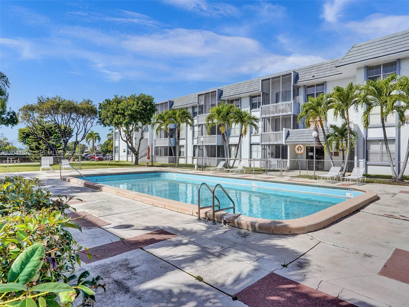 A rectangular swimming pool sits on a concrete deck in front of a multi-story apartment building — 6705 NW 169th St # C112, Hialeah FL 33015, HIALEAH, FL