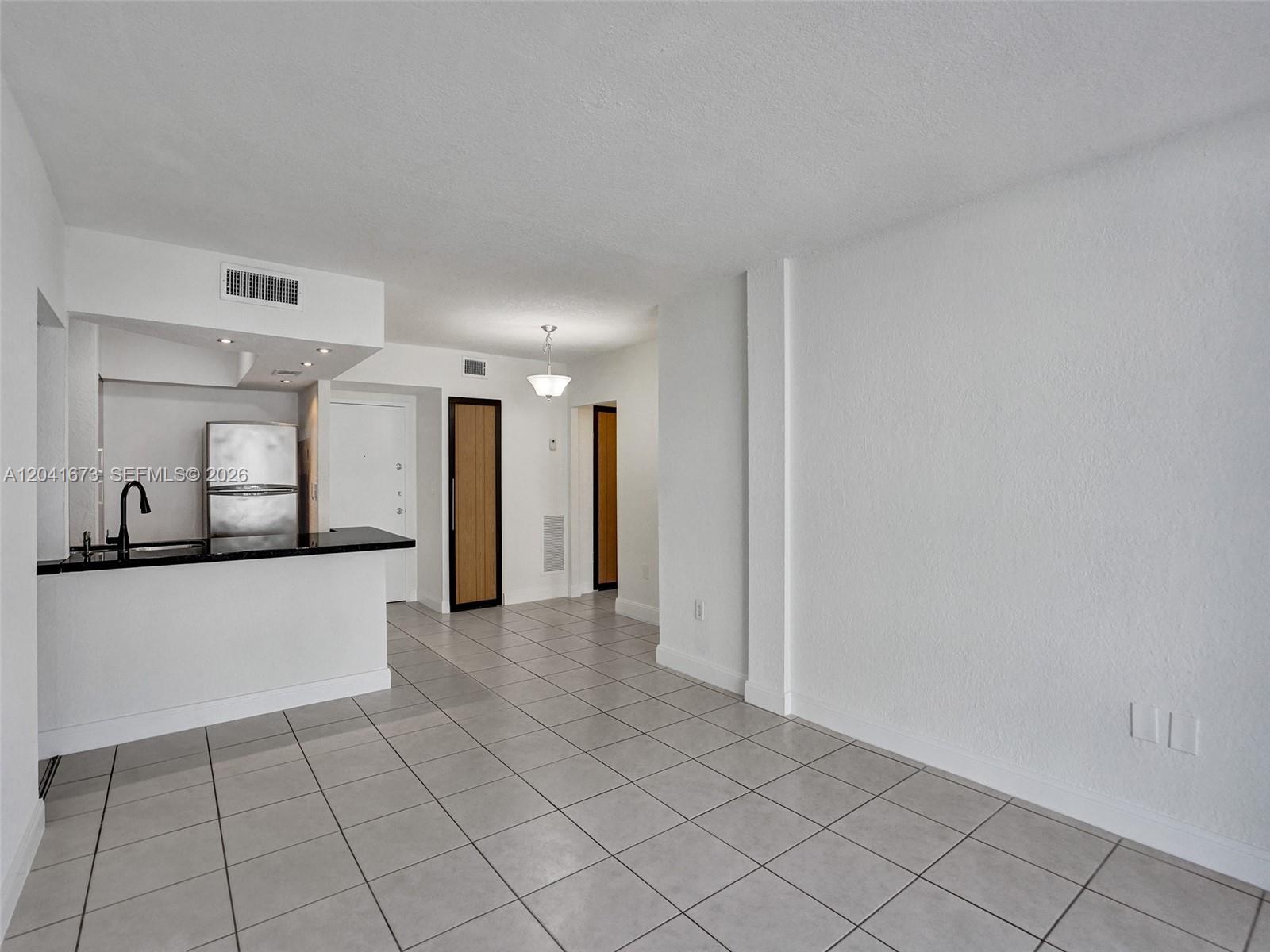 A kitchen with a breakfast bar and tiled floors opens into a living area — 6705 NW 169th St # C112, Hialeah FL 33015, HIALEAH, FL
