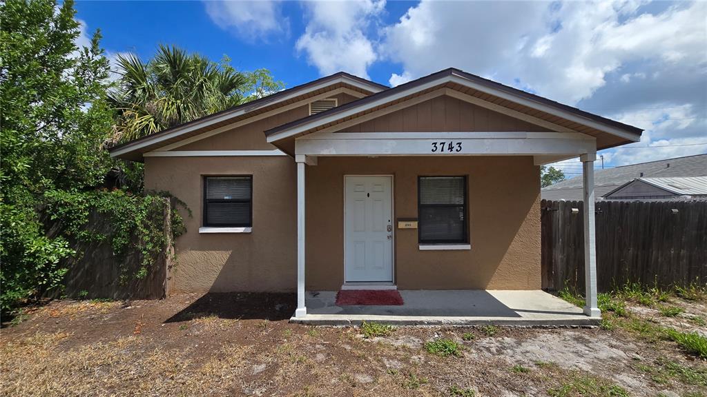 A tan, single-story house with a covered front porch and a wooden fence — 3743 1ST AVENUE S, ST PETERSBURG, FL