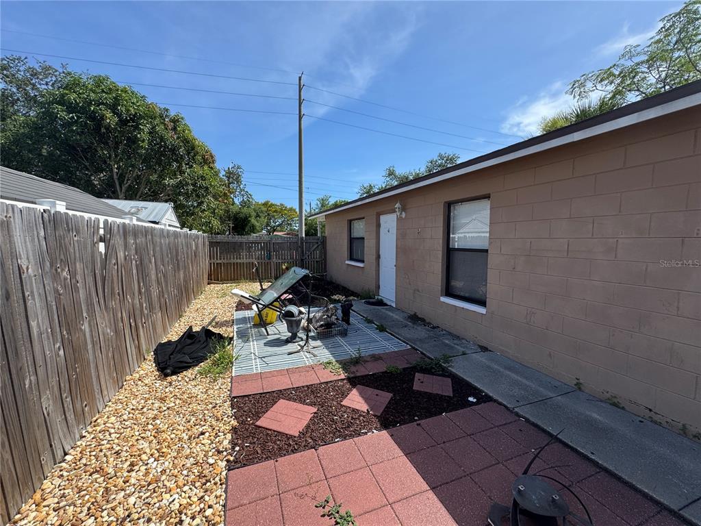 A view of a concrete block building exterior with a small patio and wooden fence — 3743 1ST AVENUE S, ST PETERSBURG, FL