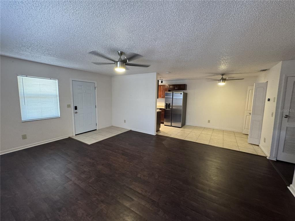 An open-concept living area features dark wood-look flooring, a tiled kitchen space, and ceiling fans — 3743 1ST AVENUE S, ST PETERSBURG, FL