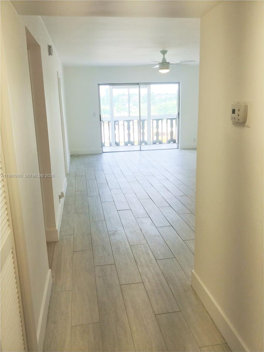 A bright living area features light wood-look tile flooring and a sliding glass balcony door — 215 SE 3rd Ave # 307C, Hallandale Beach FL 33009, HALLANDALE BEACH, FL
