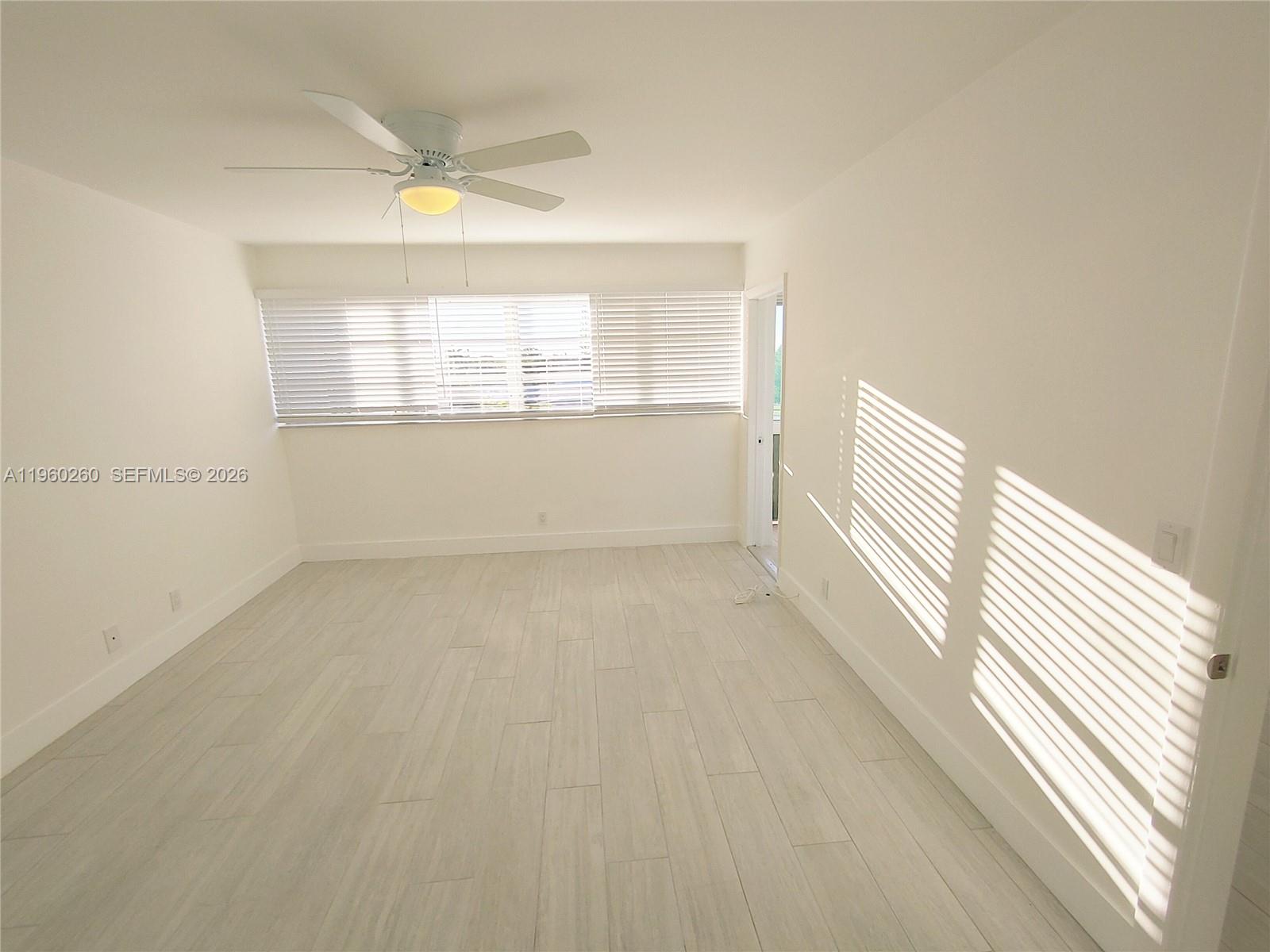 A bright, empty room features white walls, light wood-look flooring, and a ceiling fan — 215 SE 3rd Ave # 307C, Hallandale Beach FL 33009, HALLANDALE BEACH, FL
