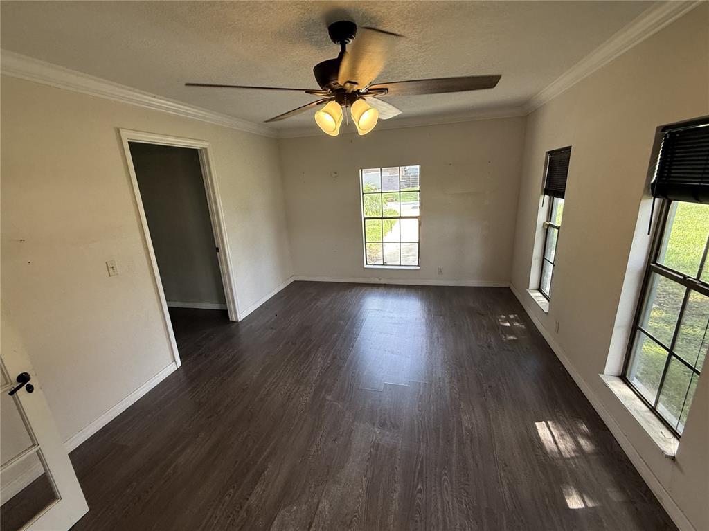 An empty room features dark wood-look flooring, a ceiling fan, and three windows — 205 TRACY WAY, LAKELAND, FL