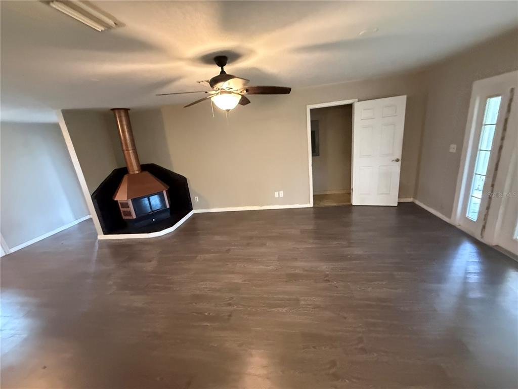 A living room features wood-look flooring, a ceiling fan, and a copper-hooded fireplace — 205 TRACY WAY, LAKELAND, FL