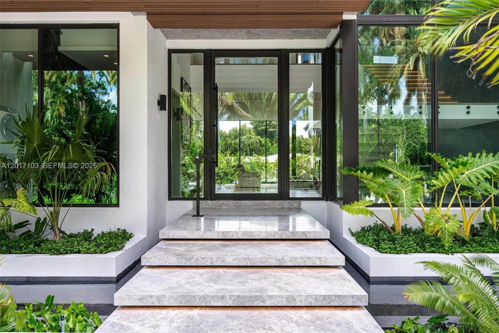 A modern entryway features marble steps leading to a glass front door with side panels — 2520 Shelter Ave, Miami Beach FL 33140, MIAMI BEACH, FL