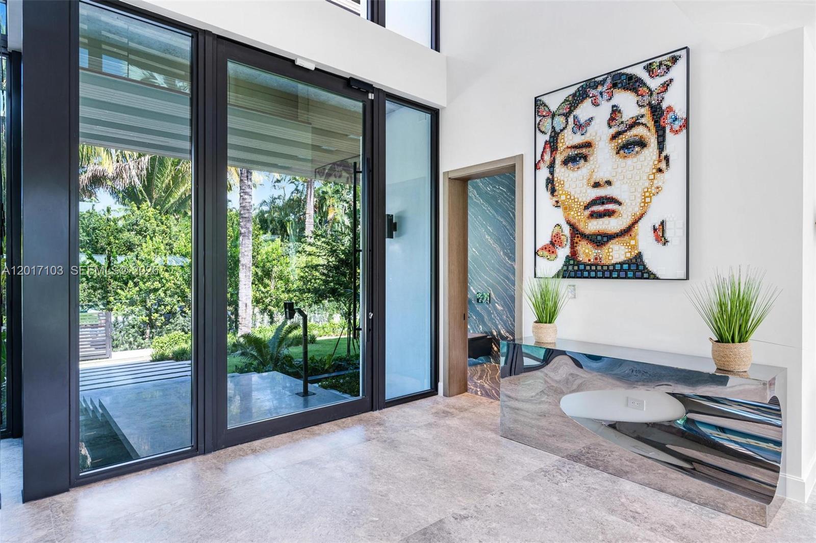 A modern entryway features large glass doors, a mirrored console table, and a mosaic portrait — 2520 Shelter Ave, Miami Beach FL 33140, MIAMI BEACH, FL