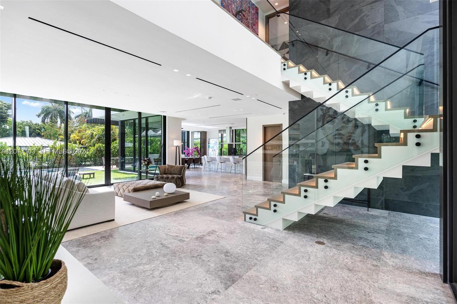 A modern living room features a floating staircase, marble floors, and floor-to-ceiling glass walls — 2520 Shelter Ave, Miami Beach FL 33140, MIAMI BEACH, FL