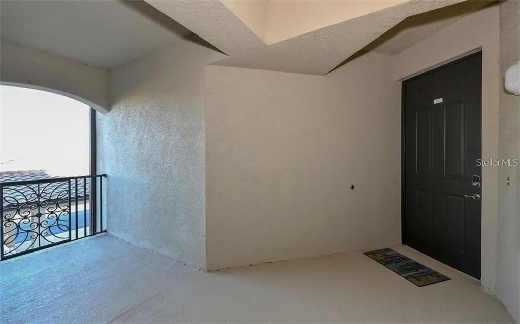 An exterior entryway features a dark door, a welcome mat, and a decorative metal railing — 16904 VARDON TERRACE UNIT 201, LAKEWOOD RANCH, FL