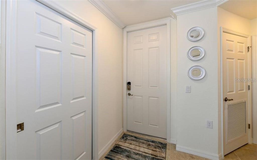 An entryway features a white front door, a closet, and three circular wall mirrors — 16904 VARDON TERRACE UNIT 201, LAKEWOOD RANCH, FL