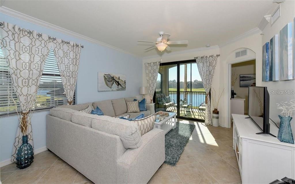 A living room features a sectional sofa, a ceiling fan, and a sliding glass door — 16904 VARDON TERRACE UNIT 201, LAKEWOOD RANCH, FL