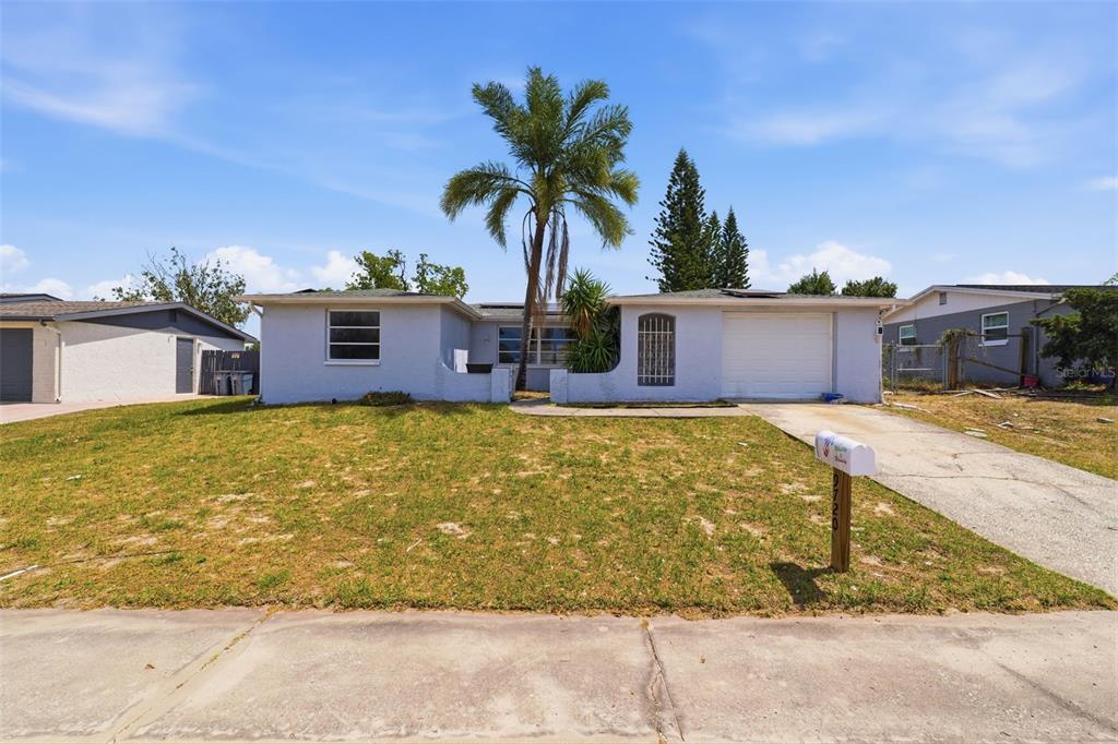 A single-story house with a palm tree, a white garage, and a front lawn — 9720 RAINBOW LANE, PORT RICHEY, FL