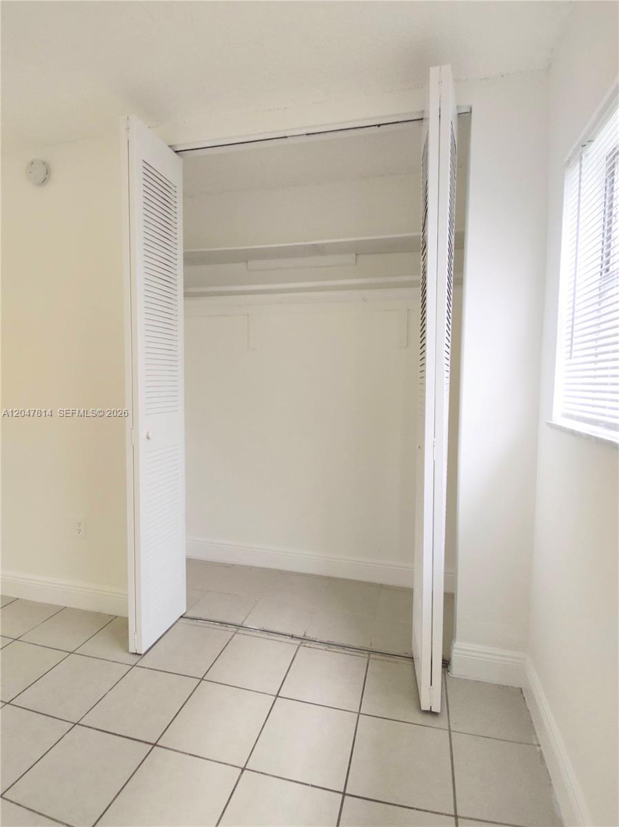 A room features white walls, light-colored floor tiles, and an open closet with louvered doors — 1265 W 24th St # 108, Hialeah FL 33010, HIALEAH, FL
