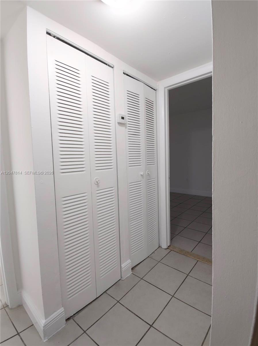 A hallway features white louvered closet doors and light-colored floor tiles — 1265 W 24th St # 108, Hialeah FL 33010, HIALEAH, FL