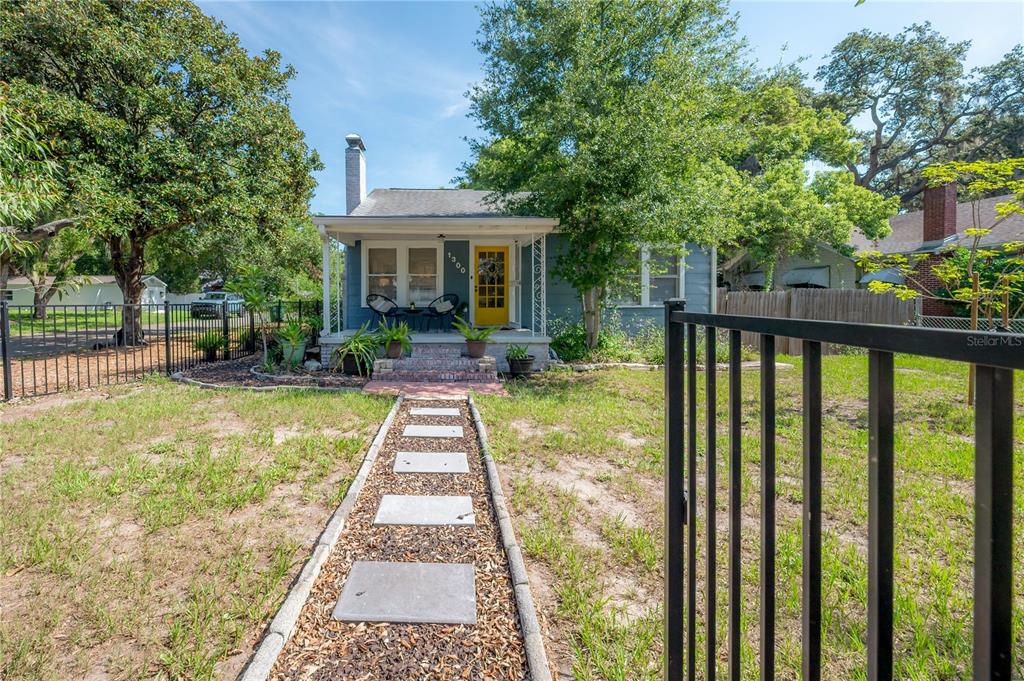 A blue cottage with a yellow front door and a stone walkway leading to the porch — 1300 E HENRY AVENUE, TAMPA, FL