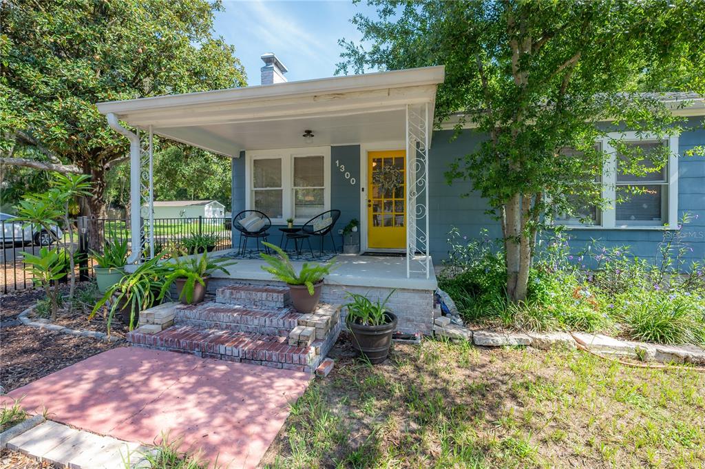 A blue house with a yellow front door and a covered brick porch — 1300 E HENRY AVENUE, TAMPA, FL