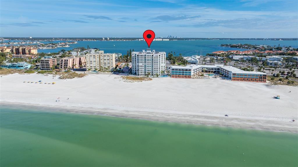 An aerial view of a white beachfront high-rise condominium building with a red location pin — 4950 GULF BOULEVARD UNIT 207, ST PETE BEACH, FL