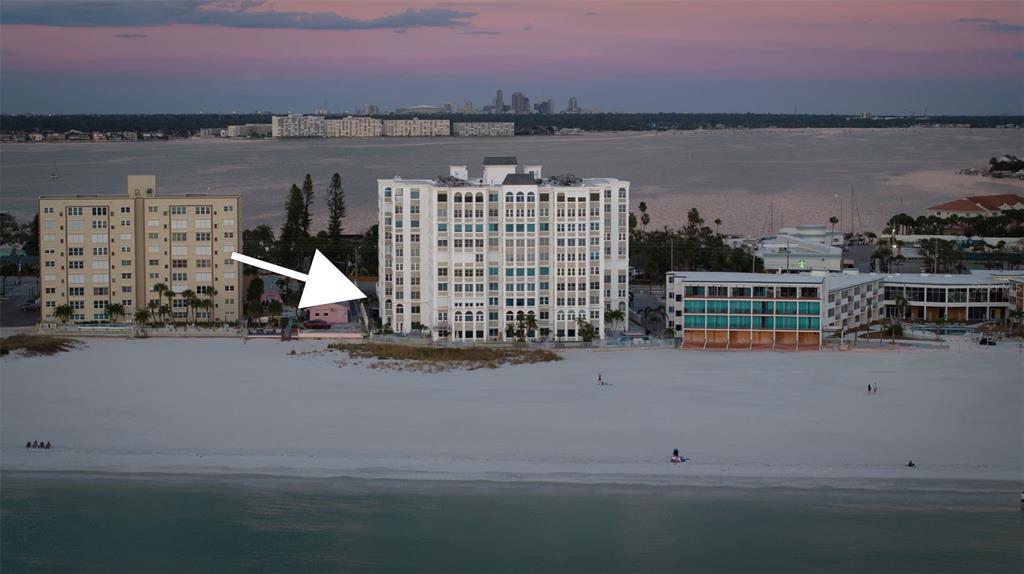 This real estate listing features a beachfront condominium building overlooking the ocean and sandy beach — 4950 GULF BOULEVARD UNIT 207, ST PETE BEACH, FL