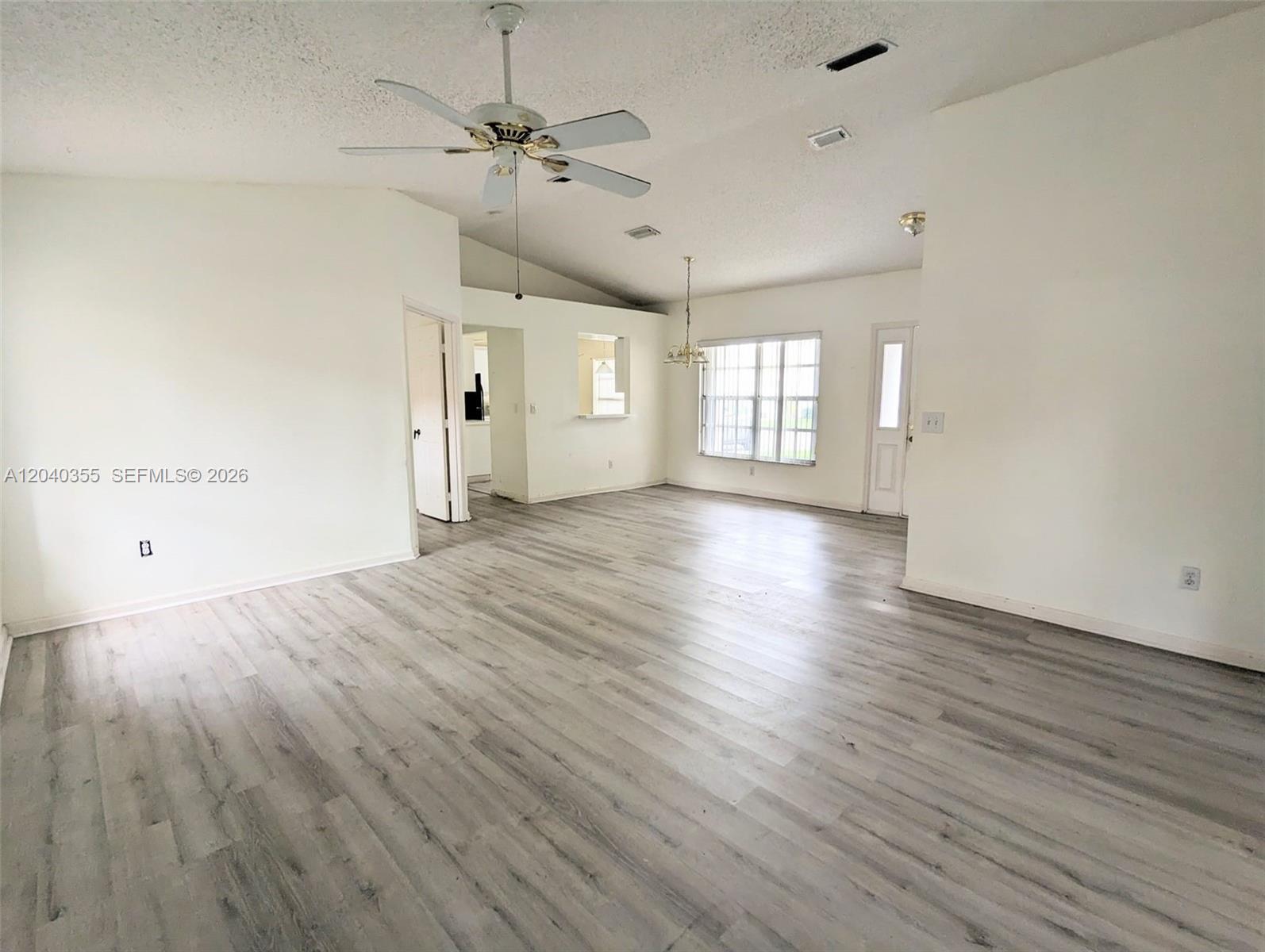 An open-concept living area features vaulted ceilings, light wood-look flooring, and a ceiling fan — 532 SE 21st Dr, Homestead FL 33033, HOMESTEAD, FL