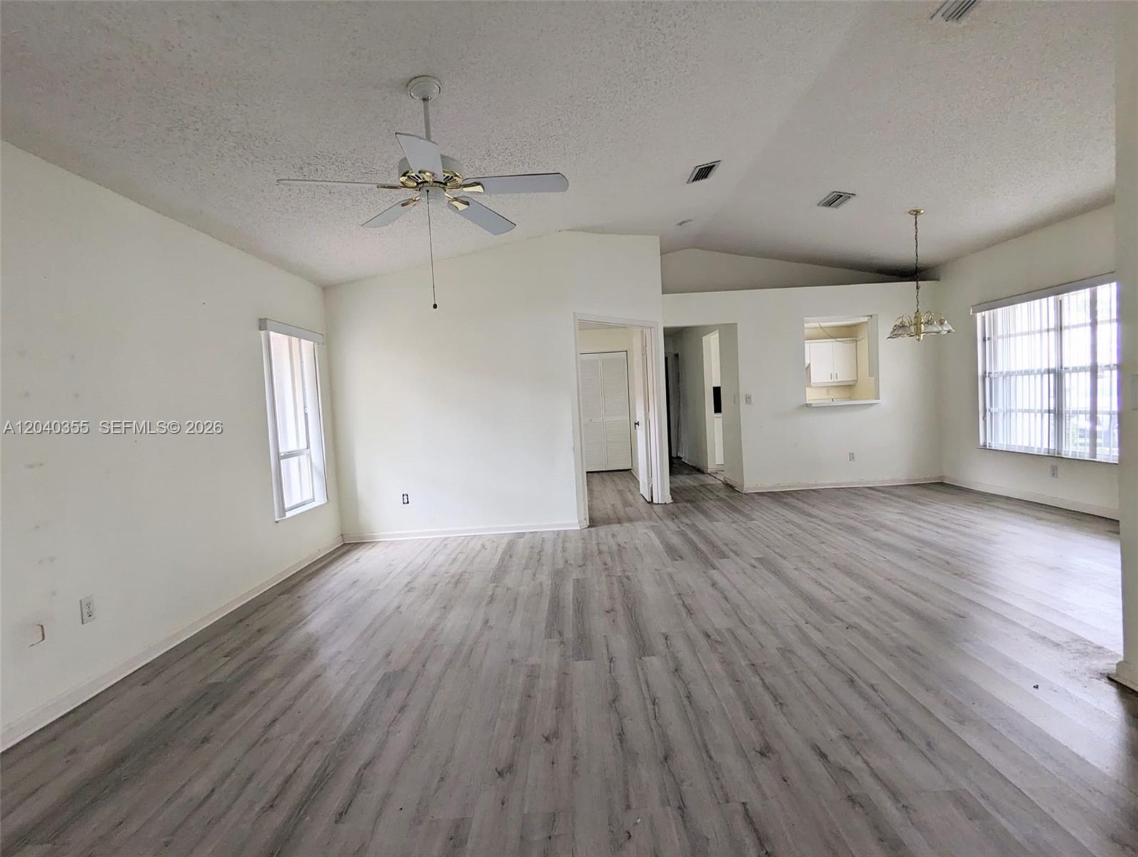 An empty living room features vaulted ceilings, a ceiling fan, and gray wood-look flooring — 532 SE 21st Dr, Homestead FL 33033, HOMESTEAD, FL